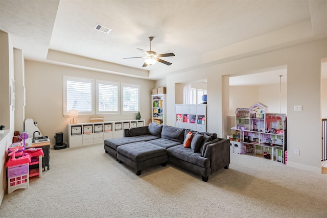 carpeted living room featuring ceiling fan and a tray ceiling