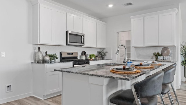 kitchen with white cabinets, an island with sink, and appliances with stainless steel finishes