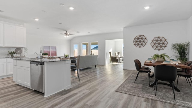 kitchen featuring stone counters, ceiling fan, stainless steel dishwasher, white cabinets, and light wood-type flooring