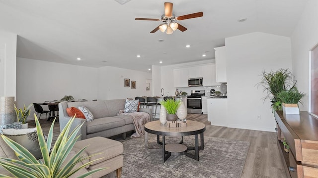 living room featuring ceiling fan, sink, and light hardwood / wood-style floors