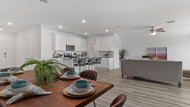 dining area featuring ceiling fan, sink, and light wood-type flooring