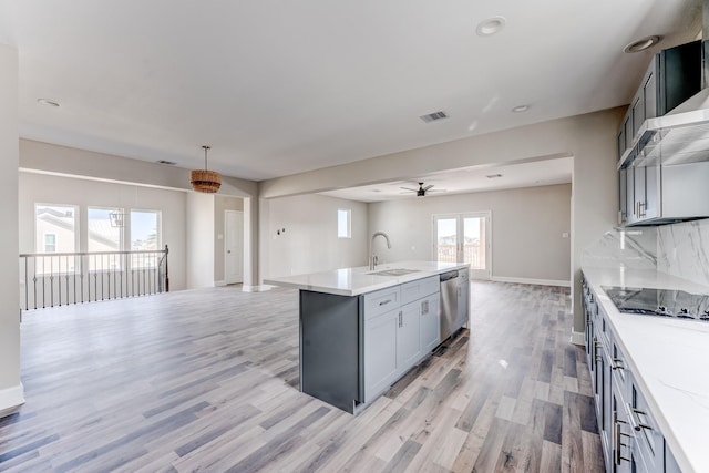 kitchen with sink, stainless steel dishwasher, decorative backsplash, black electric stovetop, and a center island with sink