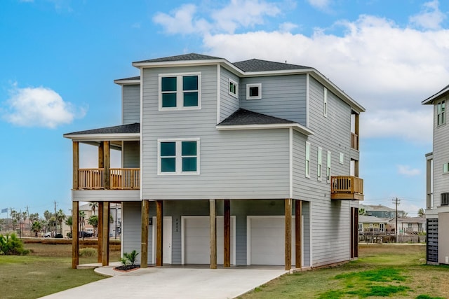 rear view of house featuring a yard, a balcony, and a garage