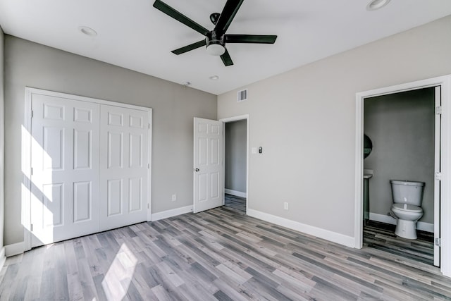 unfurnished bedroom with ceiling fan, light wood-type flooring, ensuite bathroom, and a closet