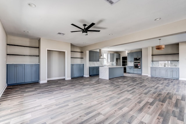 unfurnished living room with ceiling fan, sink, and light hardwood / wood-style flooring