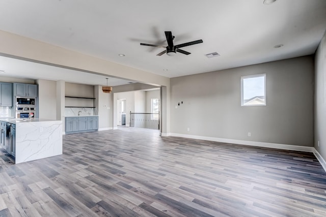 unfurnished living room featuring ceiling fan and hardwood / wood-style flooring