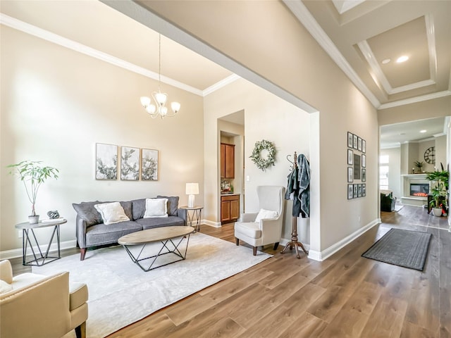 living room featuring wood-type flooring, an inviting chandelier, and crown molding