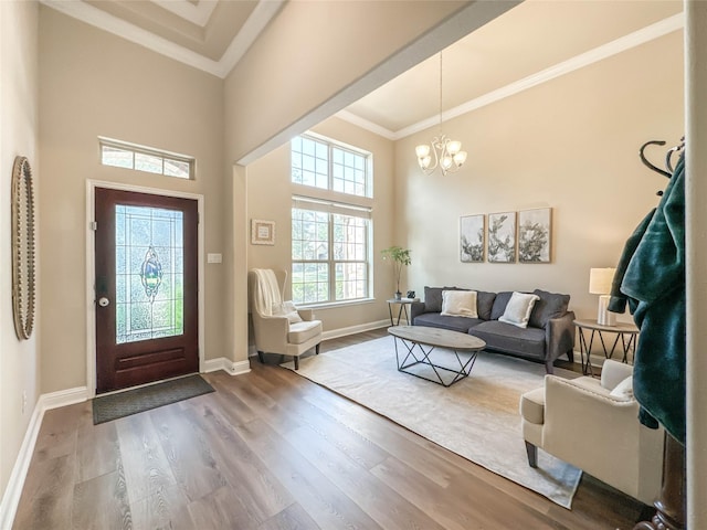 entrance foyer with wood-type flooring, an inviting chandelier, crown molding, and a high ceiling