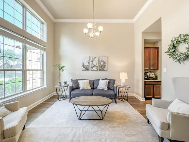 living room with wood-type flooring, an inviting chandelier, and crown molding