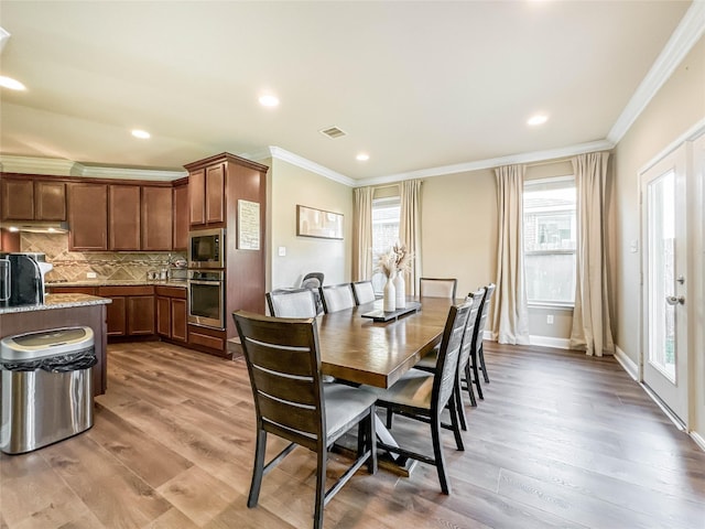 dining space with light hardwood / wood-style flooring and ornamental molding