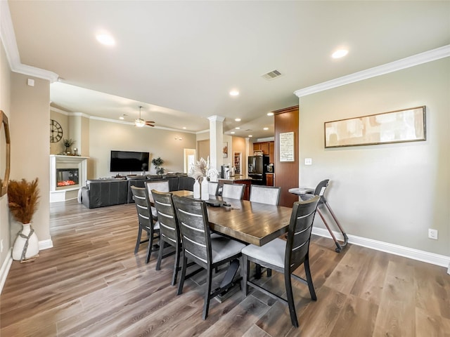 dining space featuring ornate columns, ceiling fan, light hardwood / wood-style flooring, and crown molding