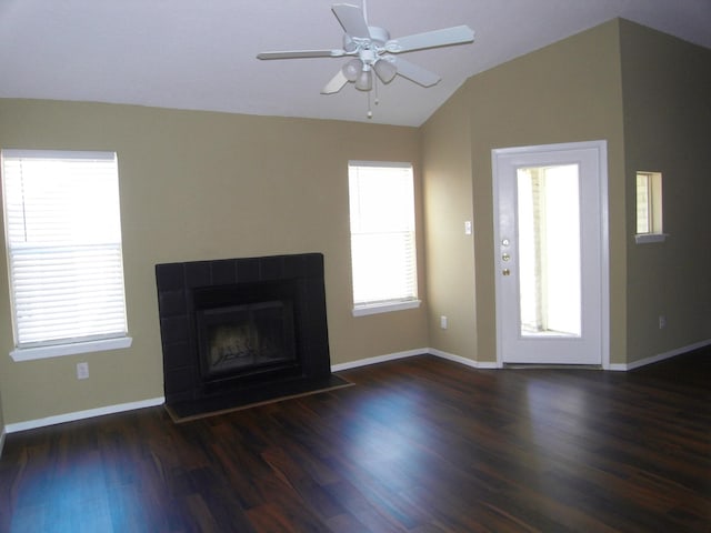 unfurnished living room featuring a tile fireplace, dark hardwood / wood-style floors, vaulted ceiling, and ceiling fan