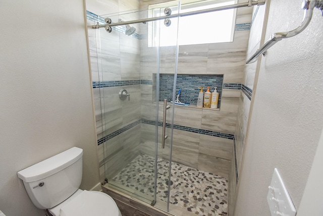 bathroom with toilet and a shower with shower door