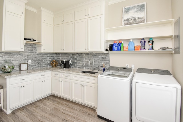 laundry room featuring cabinets, crown molding, sink, light hardwood / wood-style flooring, and separate washer and dryer