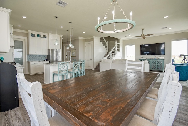 dining room featuring ceiling fan with notable chandelier, crown molding, dark wood-type flooring, and a wealth of natural light