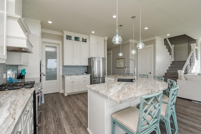 kitchen with a center island with sink, custom exhaust hood, high quality appliances, and white cabinetry