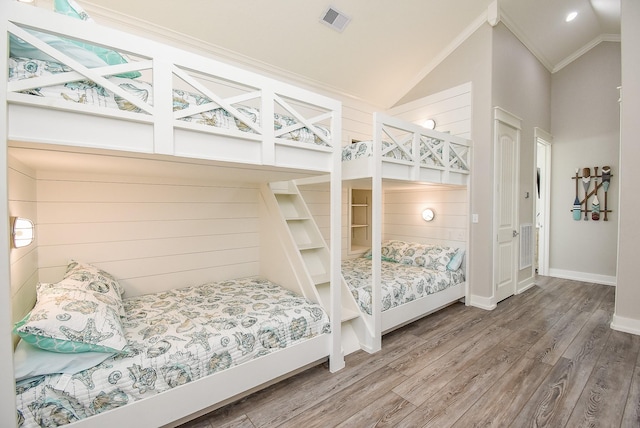 bedroom featuring lofted ceiling, wood-type flooring, and crown molding