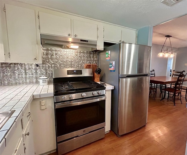 kitchen with backsplash, tile countertops, white cabinetry, and stainless steel appliances