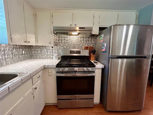 kitchen featuring tile countertops, white cabinetry, stainless steel appliances, and tasteful backsplash