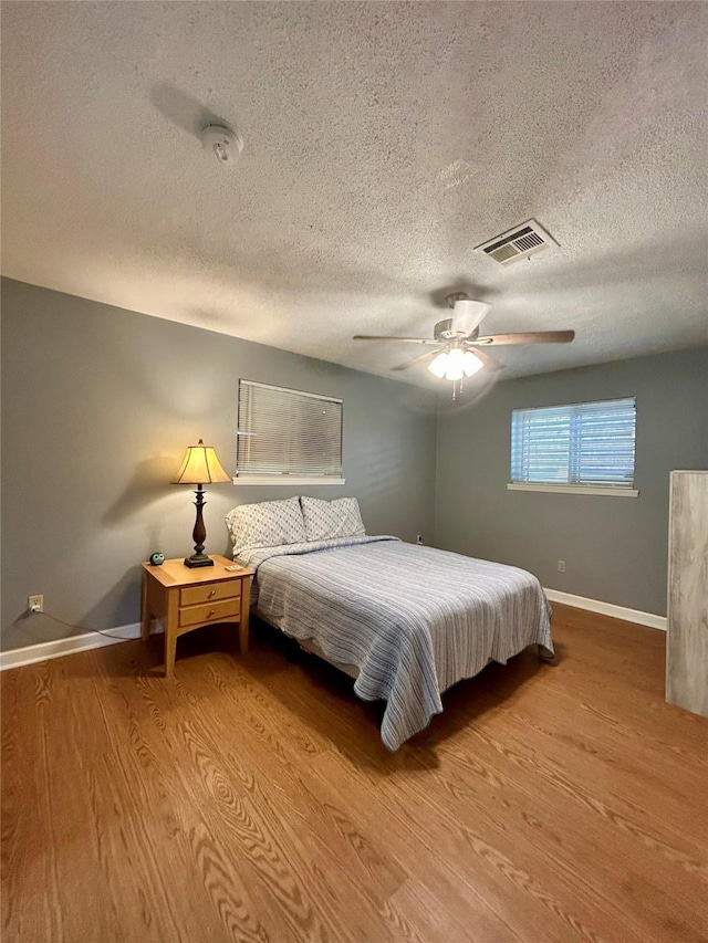 bedroom featuring ceiling fan, a textured ceiling, and hardwood / wood-style flooring