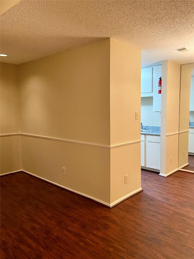 spare room featuring dark hardwood / wood-style flooring and a textured ceiling