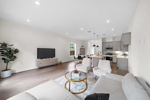 living room featuring sink and light hardwood / wood-style flooring