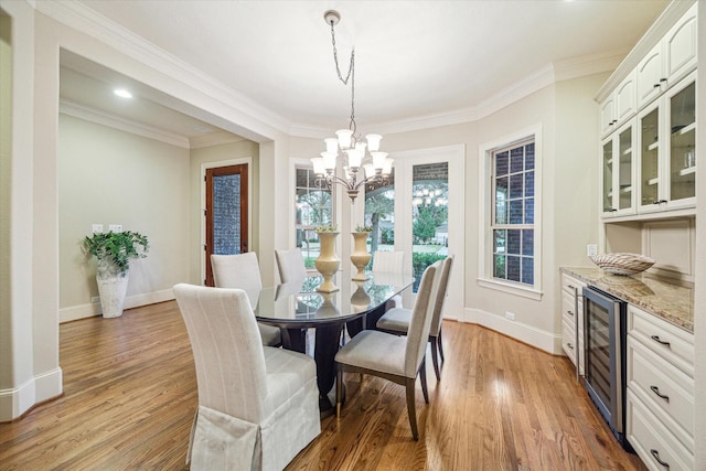 dining area with ornamental molding, light hardwood / wood-style flooring, wine cooler, and a notable chandelier