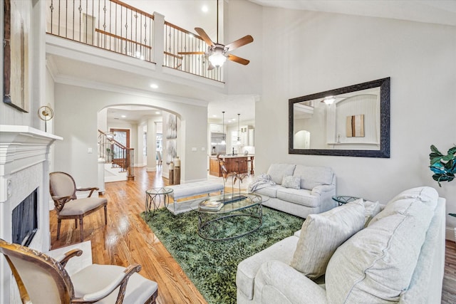 living room with wood-type flooring, a wealth of natural light, ceiling fan, and a tiled fireplace