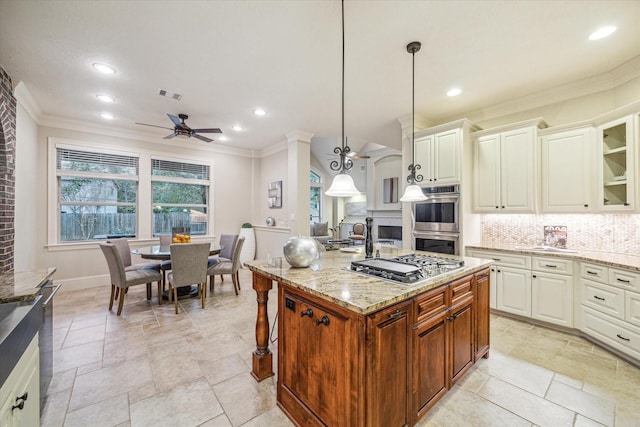 kitchen featuring backsplash, an island with sink, appliances with stainless steel finishes, decorative light fixtures, and light stone counters