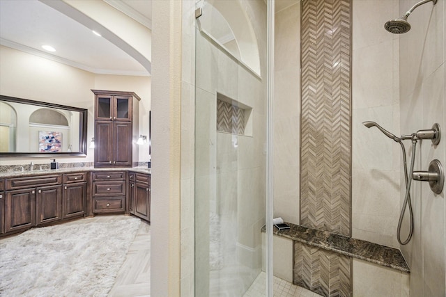 bathroom featuring tiled shower, vanity, and crown molding