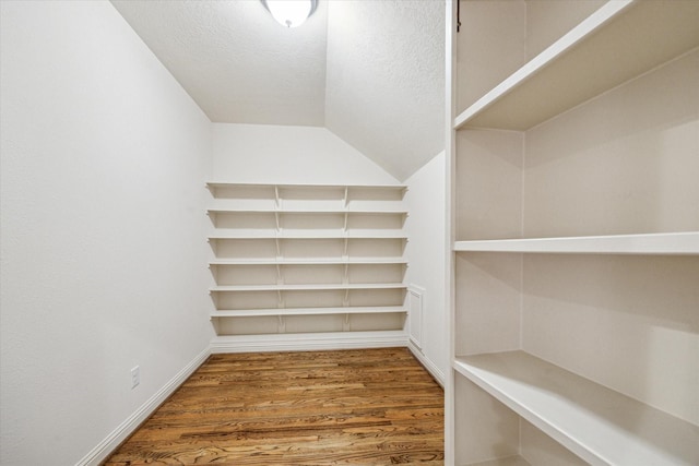 spacious closet with hardwood / wood-style flooring and vaulted ceiling