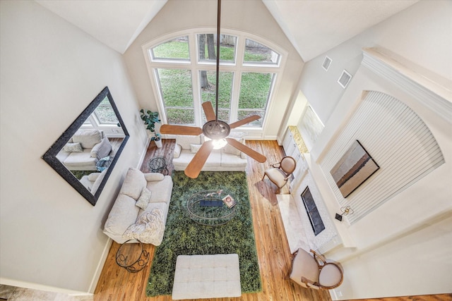 living room with ceiling fan, wood-type flooring, and high vaulted ceiling