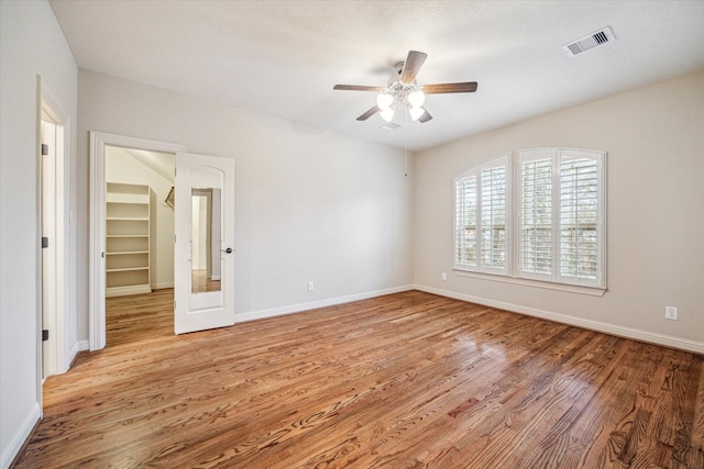 unfurnished bedroom featuring ceiling fan, a spacious closet, and light hardwood / wood-style flooring