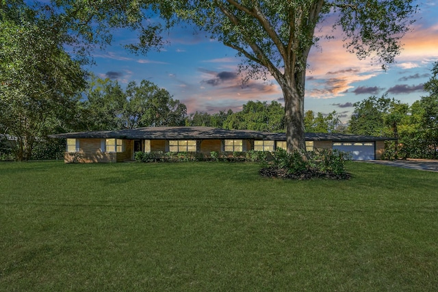 ranch-style house featuring a garage and a lawn