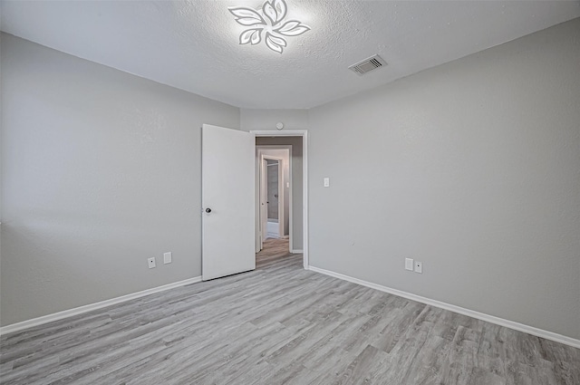 spare room with a textured ceiling and light hardwood / wood-style floors