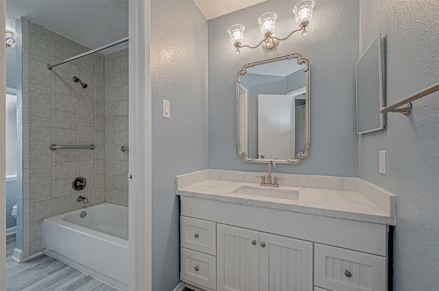 bathroom with tiled shower / bath combo, vanity, and hardwood / wood-style floors