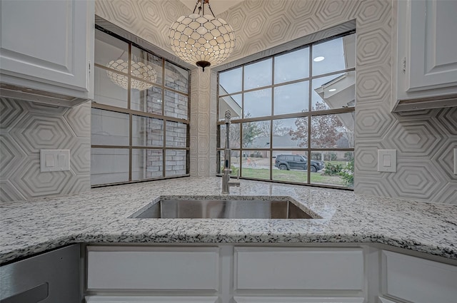 kitchen featuring light stone counters, sink, tasteful backsplash, and white cabinets