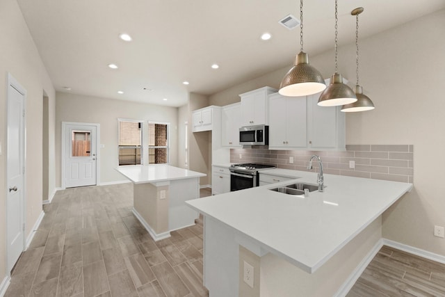 kitchen featuring stainless steel appliances, sink, white cabinets, a kitchen island, and hanging light fixtures