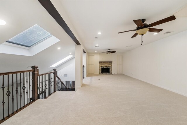 living room featuring light colored carpet, ceiling fan, and a skylight