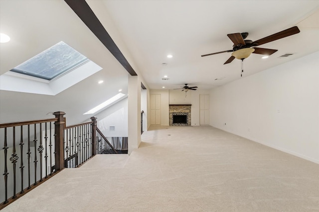 carpeted living room featuring ceiling fan and a skylight