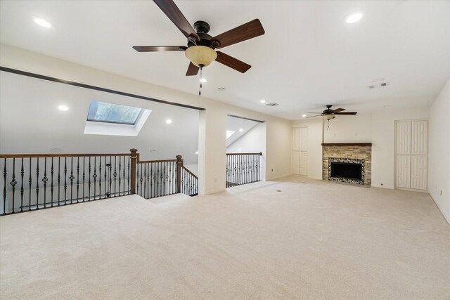 unfurnished living room featuring light carpet, ceiling fan, and a skylight