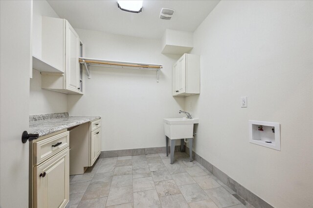 clothes washing area with cabinets and washer hookup