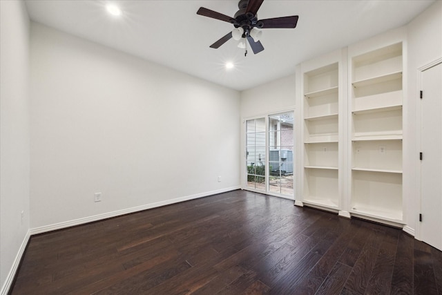 empty room with ceiling fan, dark hardwood / wood-style flooring, and built in shelves