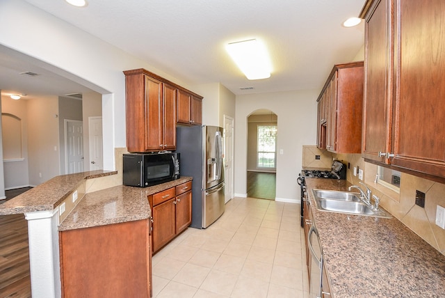 kitchen with decorative backsplash, appliances with stainless steel finishes, kitchen peninsula, a kitchen breakfast bar, and sink