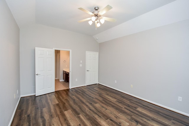 unfurnished bedroom featuring vaulted ceiling, dark hardwood / wood-style floors, ensuite bath, and ceiling fan