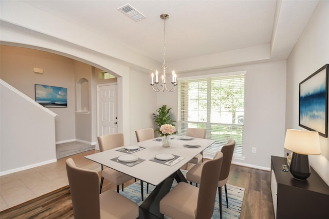 dining area featuring dark wood-type flooring and an inviting chandelier