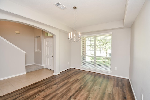 spare room with hardwood / wood-style floors and an inviting chandelier