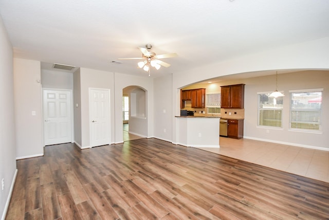 unfurnished living room with dark hardwood / wood-style floors, plenty of natural light, and ceiling fan