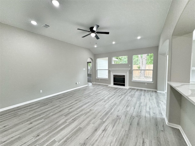 unfurnished living room with a textured ceiling, light hardwood / wood-style flooring, ceiling fan, and lofted ceiling