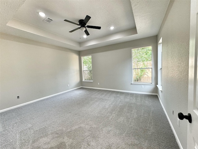 carpeted empty room with ceiling fan, a textured ceiling, and a tray ceiling